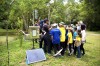 A large group of schoolchildren gather round water and rain level monitoring equipment on a riverbank as they listen to Hub researchers  thumbnail